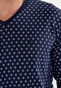 Navy V-neck shirt featuring a geometric pattern of small red and turquoise squares, made of lightweight fabric with subtle texture.