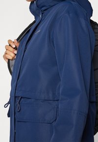 Navy blue waterproof jacket with a hood, featuring a two-way front zipper, front pockets, and adjustable drawstrings at the waist.
