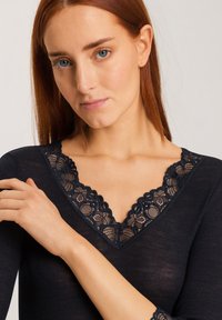 Top a coste navy con scollatura a V, caratterizzato da un elegante bordo in pizzo nero. Maniche lunghe con dettagli in pizzo ai polsini. Tessuto morbido e testurizzato.