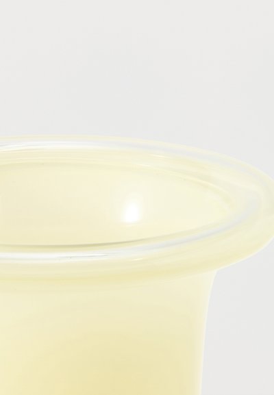 Gros plan clair d'un couvercle de récipient en silicone transparent jaune avec des bords arrondis sur fond blanc.