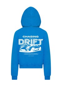 Felpa blu con cappuccio che presenta una stampa grafica sul retro di un'auto e testo. Il materiale è morbido, con vestibilità standard e polsini elastici.