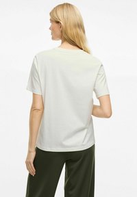 Kreemivärvi lühikeste varrukatega puuvillane T-särk, millel on ümar kaelus ja mugav lõige. Sile tekstuur, lihtne disain, ilma mustrite või aktsentideta.