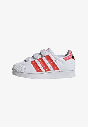 White sneakers with three red stripes featuring heart patterns, Velcro straps, and a textured rubber sole.