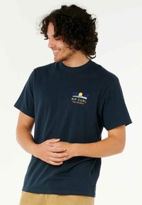 Mørkeblå bomulds t-shirt med korte ærmer og rund hals. Frontgrafik inkluderer en sol og palmer med teksten "RIP CURL THE SEARCH."