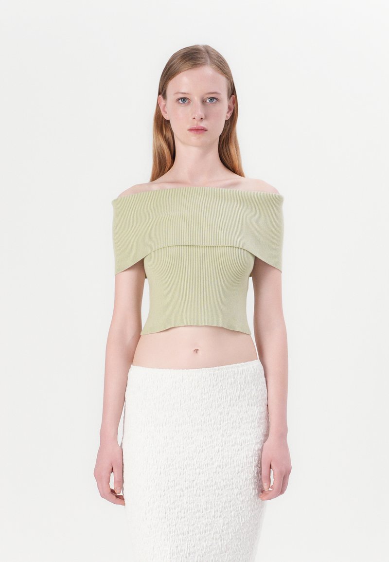 Top corto de canalé sin hombros en verde claro, con un diseño ajustado. Combinado con una falda blanca texturizada. Textura de tela suave.