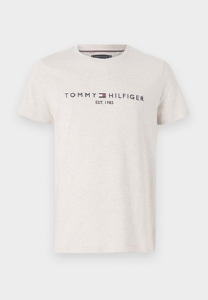 Šviesiai pilkas Tommy Hilfiger marškinėliai su tamsiai mėlynu logotipu ir raudonos, baltos, mėlynos spalvų vėliavos emblemu, tekstas "EST. 1985" centruotas ant krūtinės.