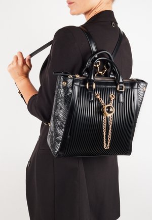 Czarna torebka na ramię o żłobionej fakturze, ze złotymi elementami i łańcuchowym detalem. Posiada gładką skórę i akcenty w skórę węża, ma strukturalny kształt oraz podwójne uchwyty.