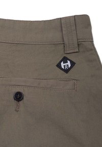Kakifärgade byxor gjorda av ett lätt tyg, med knappstängning, ficka med lappar och broderad logotyp i svart och vitt på midjebandet.