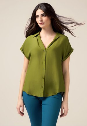 Groene blouse met korte mouwen, met kraag, knoopsluiting aan de voorkant en een lose pasvorm. Gepaard met blauwe, slim fit broek. Soepele stof met een lichte glans.