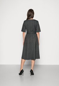 Szara sukienka do kolan z krótkimi rękawami, z paskiem w pasie i subtelną fakturą. Nosi się z czarnymi szpilkami, prezentującymi prosty, elegancki design.