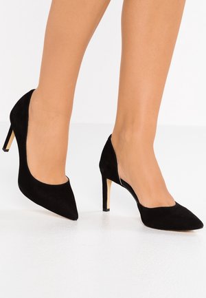 Sorte ruskind højhælede sko med spidse tåer og et udsnit design. Skoene har en tynd stilettohæl og en glat, mat overflade.