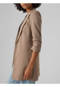 Světlý béžový blejzr s vypasovaným střihem, klopami s výřezem, vyhrnutými rukávy a bočními kapsami, vyrobený z hladké, lehké látky.