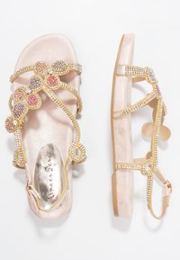 Růžově zlaté ploché sandály se zlatými a vícebarevnými kamínkovými květinovými popruhy, s přezkou kolem kotníku a značkovou kovovou stélkou.