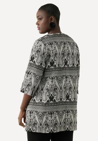 Tunika lunga a righe in bianco e nero con design paisley, maniche a tre quarti e una vestibilità ampia, realizzata in un tessuto leggero.