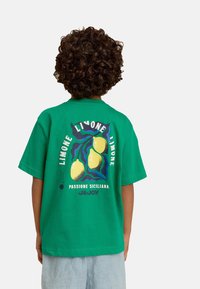 Groene katoenen t-shirt met een grafisch ontwerp van citroenen, golven en tekst. Losse pasvorm met korte mouwen en een ronde hals.