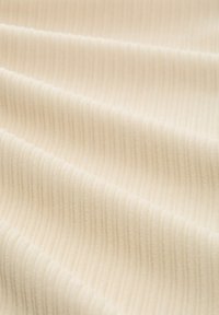 Roomkleurige ribstof met zichtbare textuur, voorzien van zachte lijnen en plooien. Het oppervlak oogt glad en licht rekbaar.