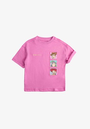 Pink t-shirt med korte ærmer med tre tegneseriefigurs ansigter og tekst "The toys are back together" på frontens højre side.