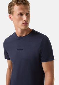 Mørkeblå bomulds-T-shirt med rund hals og korte ærmer. Har et lille broderet mærkenavn "BOGNER" på brystet.