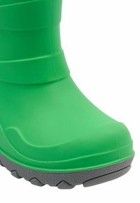 Botte en caoutchouc verte avec un bout arrondi, une semelle grise texturée et des rainures horizontales sur le haut pour une meilleure adhérence et flexibilité.