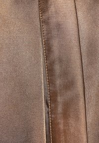 Bronze fabric with a smooth, satin-like texture. Features a straight edge with a fine, contrasting stitch along the seam.