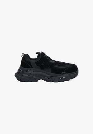 Schwarzer Sportschuh mit dicker Sohle, Mesh- und Velour-Paneelen sowie Schnürverschluss, von der Außenseite auf weißem Hintergrund gezeigt.
