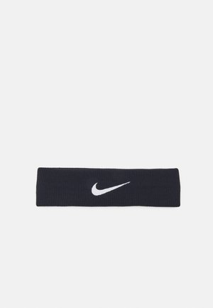 Curea tricotată de culoare marină, cu un logo alb Nike. Textură netedă, formă rectangulară, concepută să se potrivească în siguranță în jurul capului.