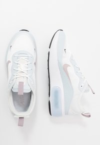 Valkoiset ja vaaleansiniset Nike-tennarit, joissa on sileä kankainen päällinen, kontrastiväriä pinkkiä, musta pohja ja näkyvä ilmatyyny.