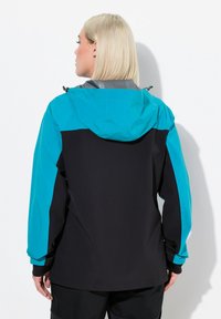 Veste imperméable noire, avec des manches et une capuche teal. Elle dispose d'un cordon de serrage sur la capuche, de textures contrastées et de poignets élastiques.