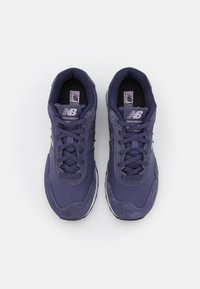 Scarpe da atletica viola con un mix di materiali lisci e testurizzati, dotate di punte arrotondate, colletto imbottito e lacci. Accenti neri sui lati.