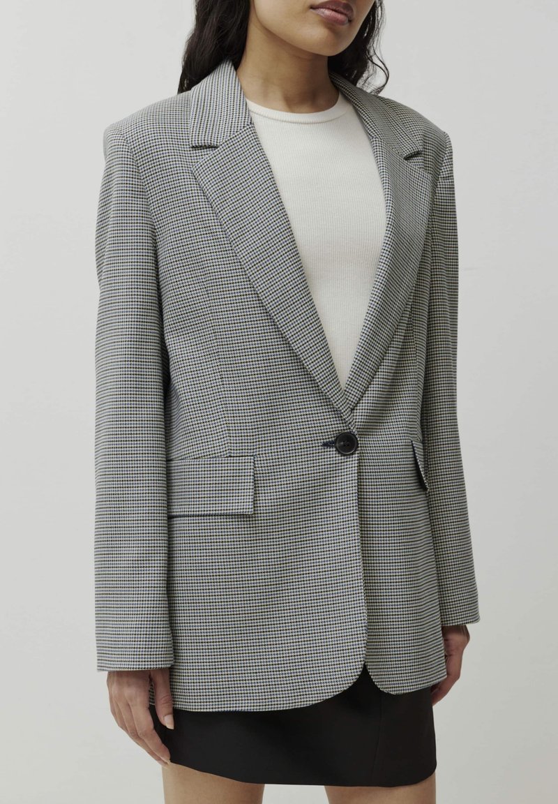 Grau und schwarzer kariertes Blazer mit einem Ein-Knopf-Verschluss, Reverskragen und zwei vorderen Taschen. Texturiert mit einer taillierten Passform.