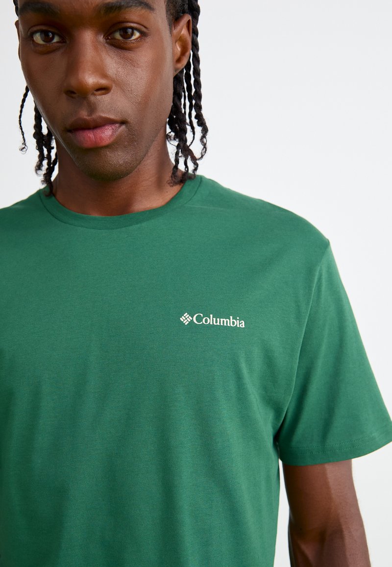 T-shirt verde in cotone con colletto a girocollo e maniche corte, con il logo bianco Columbia stampato sulla parte sinistra del petto.