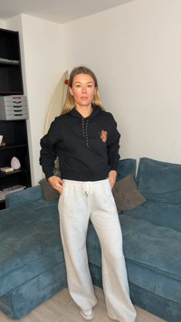 Sweat à capuche noir raccourci avec un motif de papillon et pantalon de survêtement gris, fabriqués en tissu doux. Coupe décontractée, taille élastiquée avec cordon de serrage.