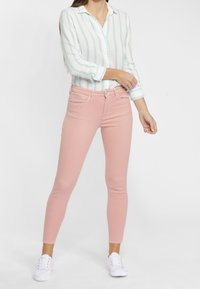 Light blue and white striped button-up shirt paired with pink skinny jeans and white sneakers. Smooth fabric and fitted design.