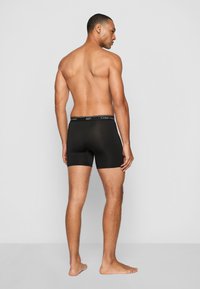 Fekete elasztikus boxer alsónemű, amely szoros illeszkedést biztosít, fekete gumis derékrésszel, amelyen a "Calvin Klein" felirat fehér színben látható.