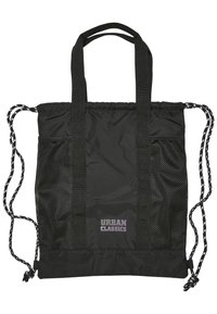 Bolsa tote negra fabricada en nylon duradero. Cuenta con bolsillos laterales de malla, cierre ajustable con cordón y doble asa. El texto dice "URBAN CLASSICS."