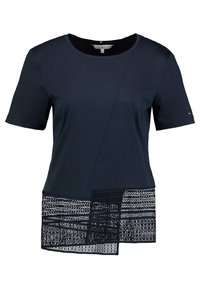 Tmavě modré tričko s krátkým rukávem, které má na spodním levém rohu texturovanou krajkovou panel, což dodává stylový kontrast.