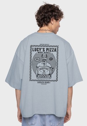 Camiseta de gran tamaño en azul claro con una impresión gráfica negra de un chef de pizza y el texto que dice "Pizza de Lucy, hecha en el infierno" y bordes a cuadros.