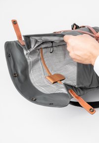 Grau gefütterte Stofftasche mit sandfarbenen Lederakzenten, ausgestattet mit einem karierten Innenfutter, einem Reißverschluss und einem kleinen Ledergriff.