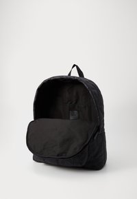 Zaino colore nero imbottito con una grande apertura, caratterizzato da una texture liscia, spallacci regolabili e una tasca interna con un'etichetta.
