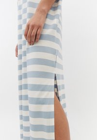 Sukienka maxi w jasnoniebieskie i białe poziome paski, wykonana z miękkiego materiału, z bocznym rozcięciem i małą metką z logo na dolnej krawędzi.