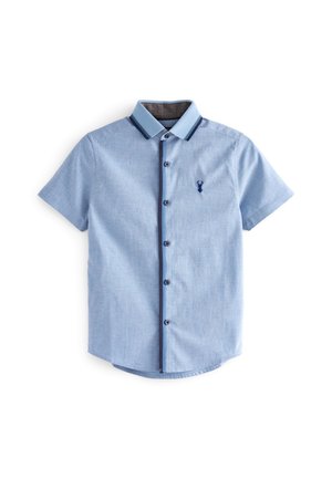 Chemise à manches courtes bleu clair avec bordure bleu foncé sur le col et la ligne de boutons, avec un petit logo de cerf bleu foncé sur la poitrine.