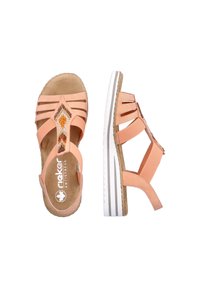 Sandale de couleur pêche avec plusieurs brides, semelle intérieure texturée, semelle en caoutchouc blanche et perles décoratives à l'avant. Bride de cheville ajustable incluse.