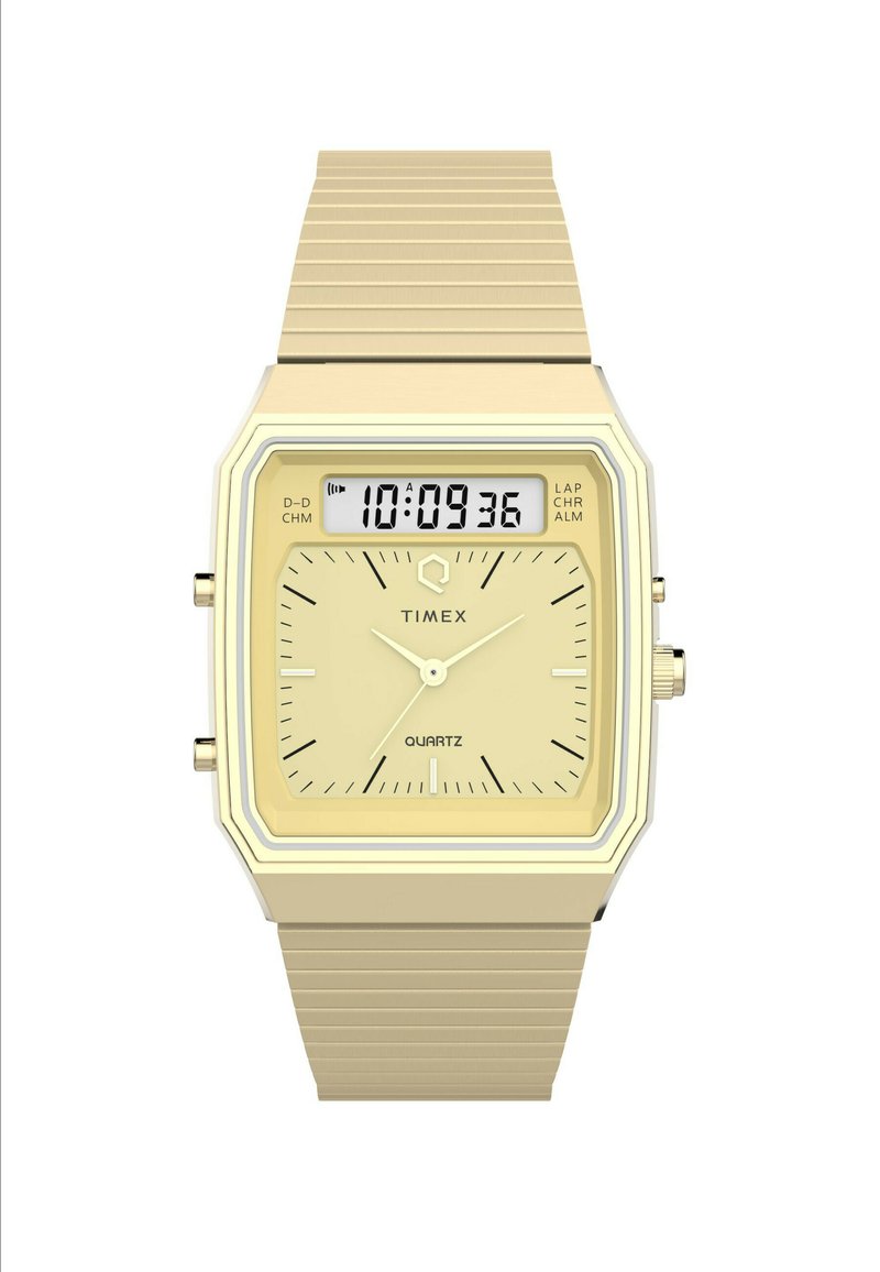 Montre Timex à quartz avec un boîtier carré doré, un affichage numérique et un bracelet en métal texturé doré. Présente des marqueurs d'heure et de minute.