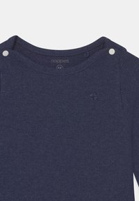 Noppies marinblå långärmad topp med ribbad textur, rund halsringning och två tryckknappar på axeln för enkel påklädning.