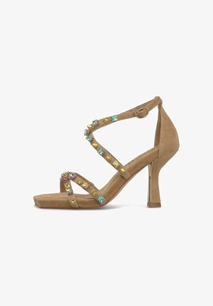 Sandale à talons hauts en daim beige avec bout carré, bride à la cheville et ornements colorés de pierres et de clous dorés sur plusieurs fines brides.