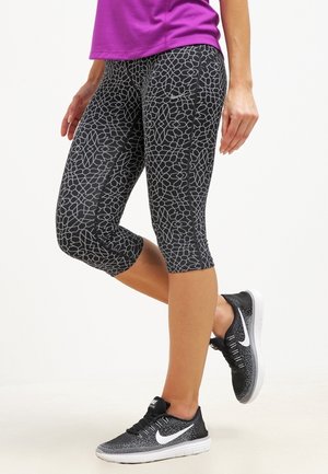 Zwarte capri leggings met een geometrisch patroon, zachte stof en een figuurvormend ontwerp, gecombineerd met zwart-witte sportschoenen.