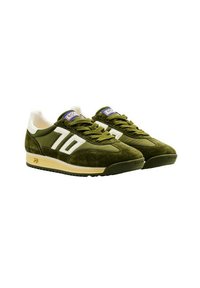Sneakers in suede verde con strisce bianche, accenti beige e colletto imbottito. Presentano una suola testurizzata e un'etichetta sulla linguetta.