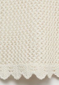 Tissu tricoté blanc avec un motif en maille ouverte et un détail de bordure festonnée, mettant en valeur un design texturé et léger.
