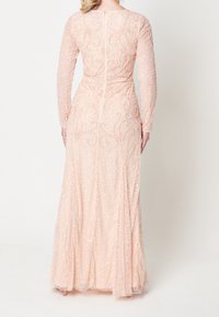 Abito rosa cipria a maniche lunghe con dettagli intricati di perline e paillettes, vita sagomata e gonna fluente. Chiusura con cerniera posteriore visibile.