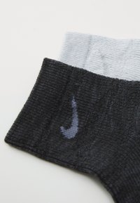 Nahaufnahme von schwarzen und grauen Nike Knöchelsocken mit geripptem Muster und dem Nike Swoosh-Logo auf dem schwarzen Abschnitt.
